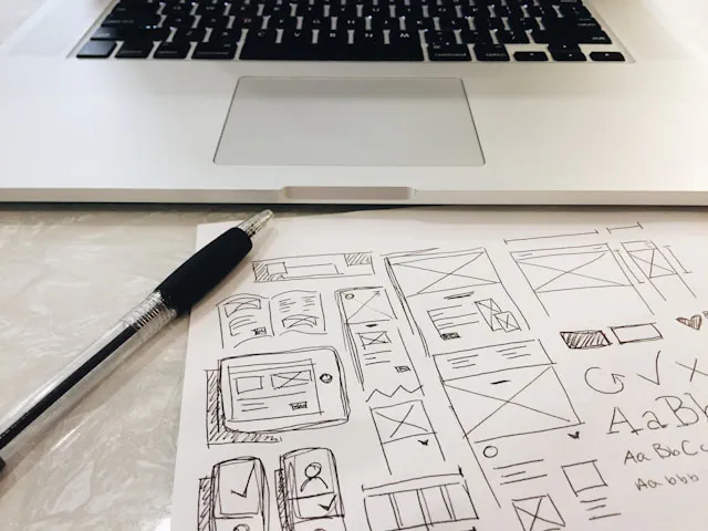 Designer planning a subscription website model with icons and laptop